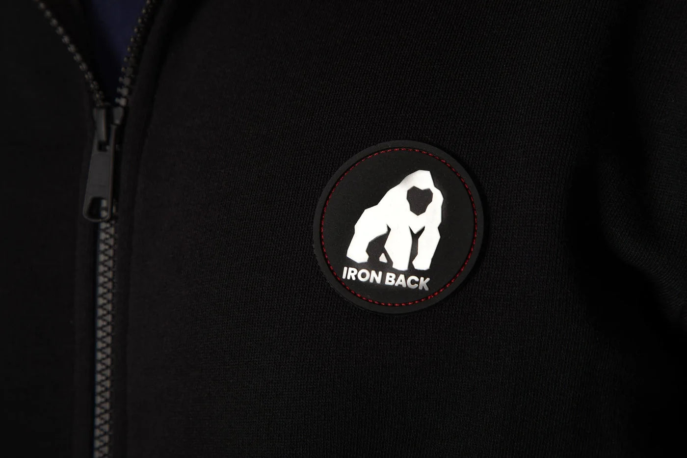 Gros plan du zip, de la matière et du patch gorille du hoodie Origins